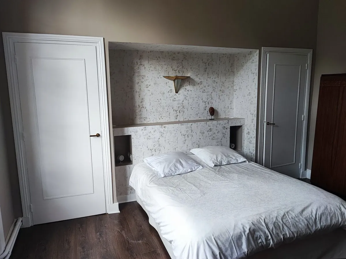Chambre avec une tête de lit en plaques de plâtre à deux niches, revêtue de papier peint